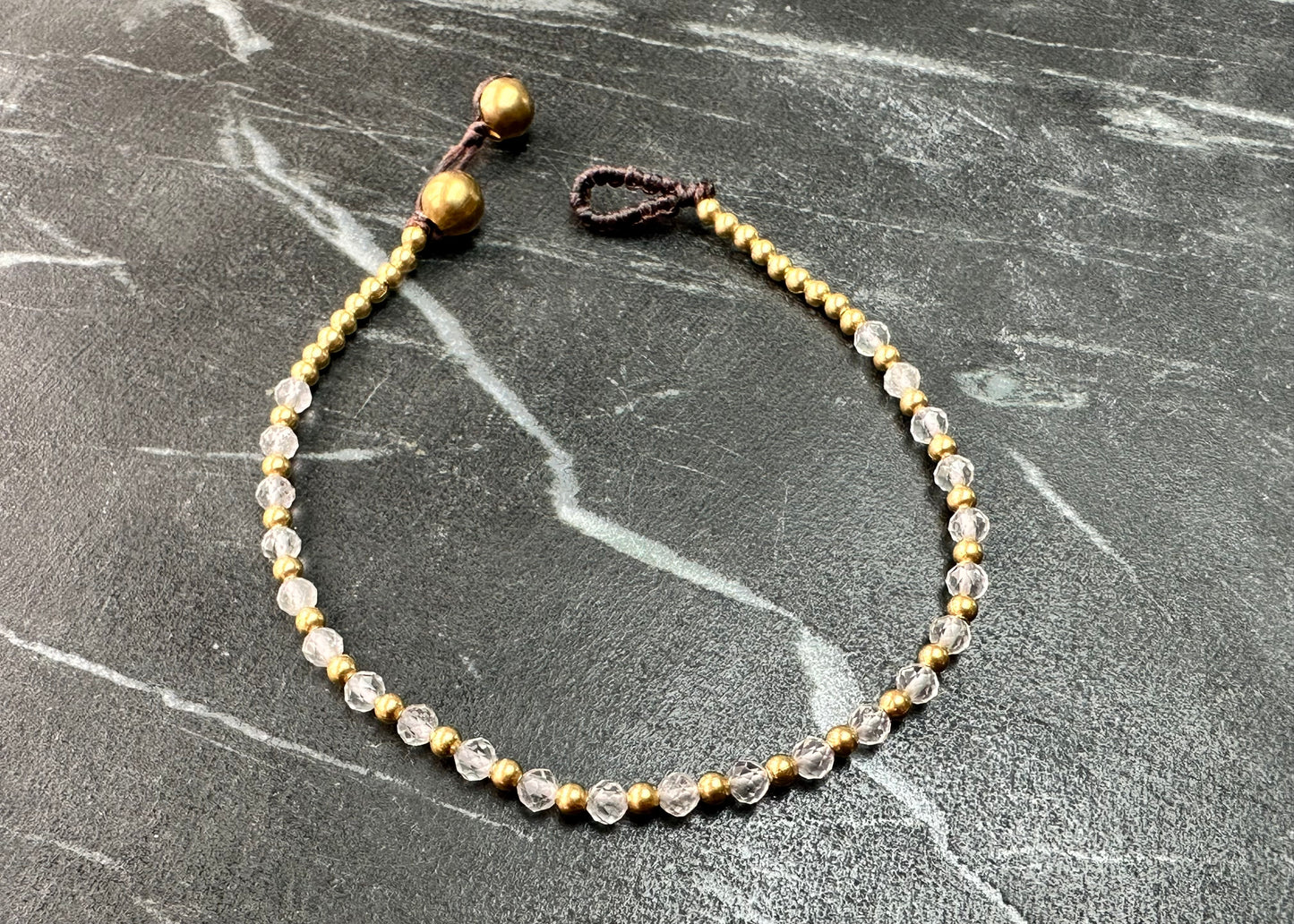 A crystal healing bracelet made of faceted White Quartz crystals on a cotton cord with brass beads