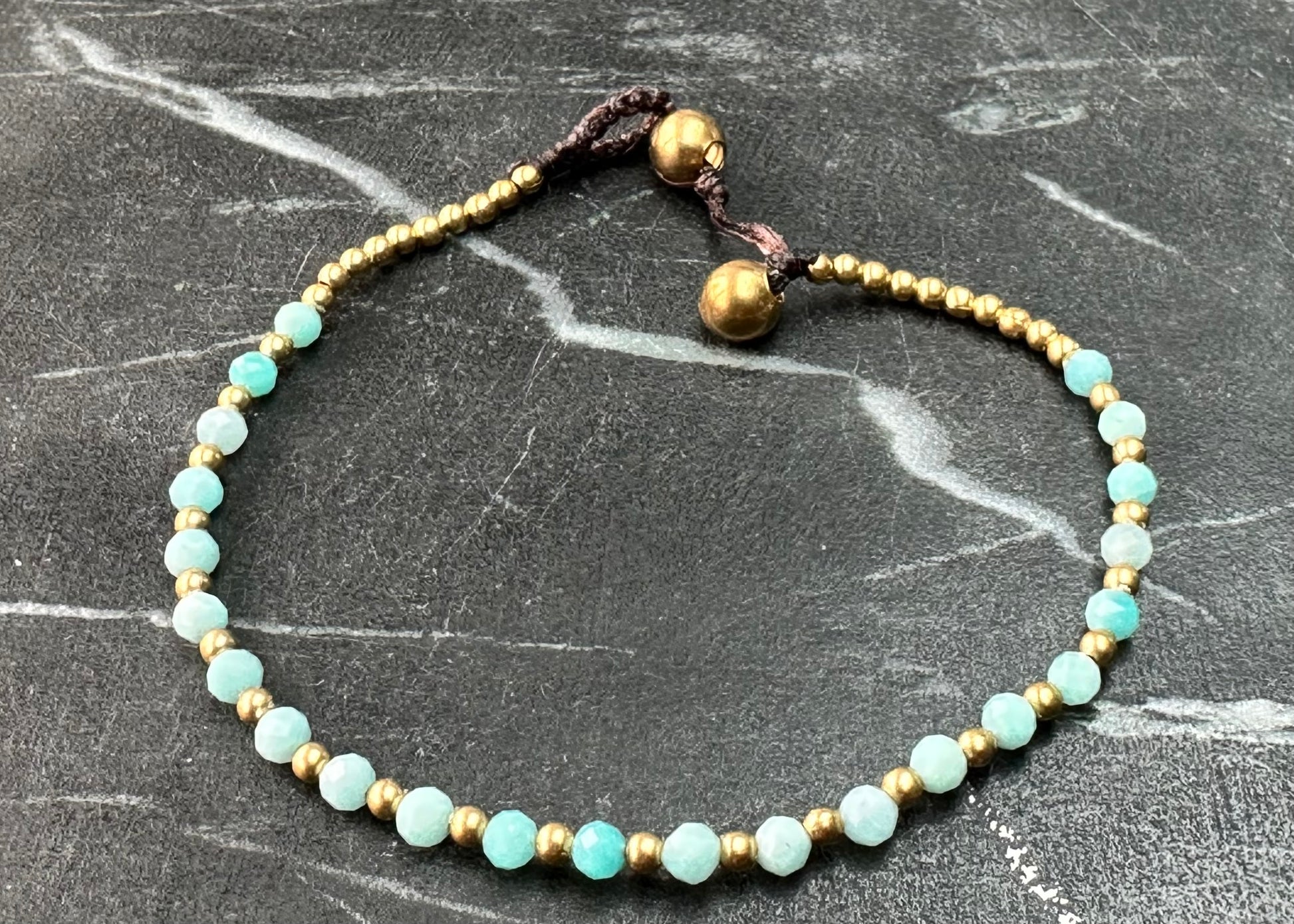 a crystal healing bracelet made of faceted Amazonite crystals on a cotton cord with brass beads