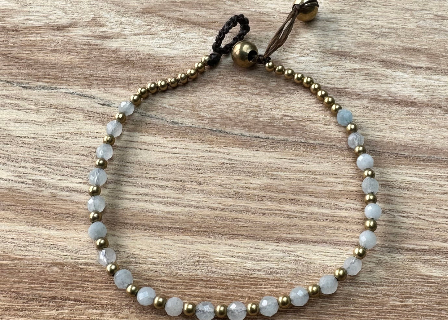 A crystal healing bracelet made of faceted Aquamarine crystals on a cotton cord with brass beads.