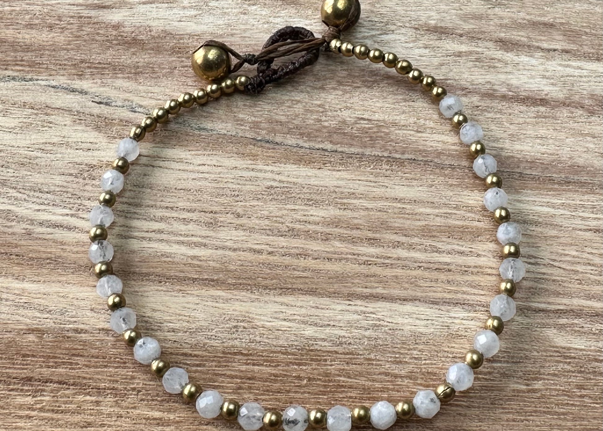 A crystal healing bracelet made of faceted White Quartz crystals on a cotton cord with brass beads