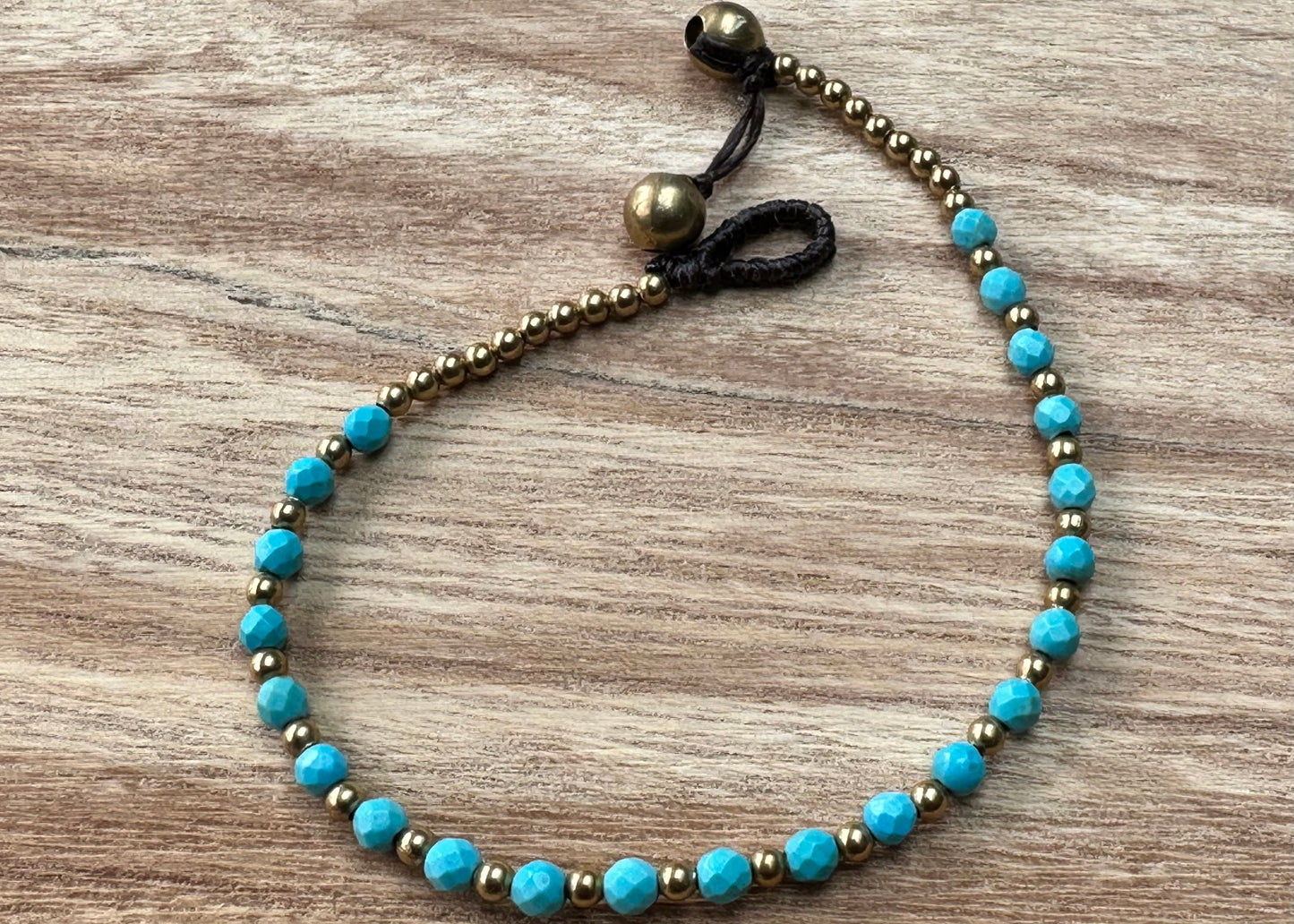 A crystal healing bracelet made of faceted Turquoise crystals on a cotton cord with brass beads.