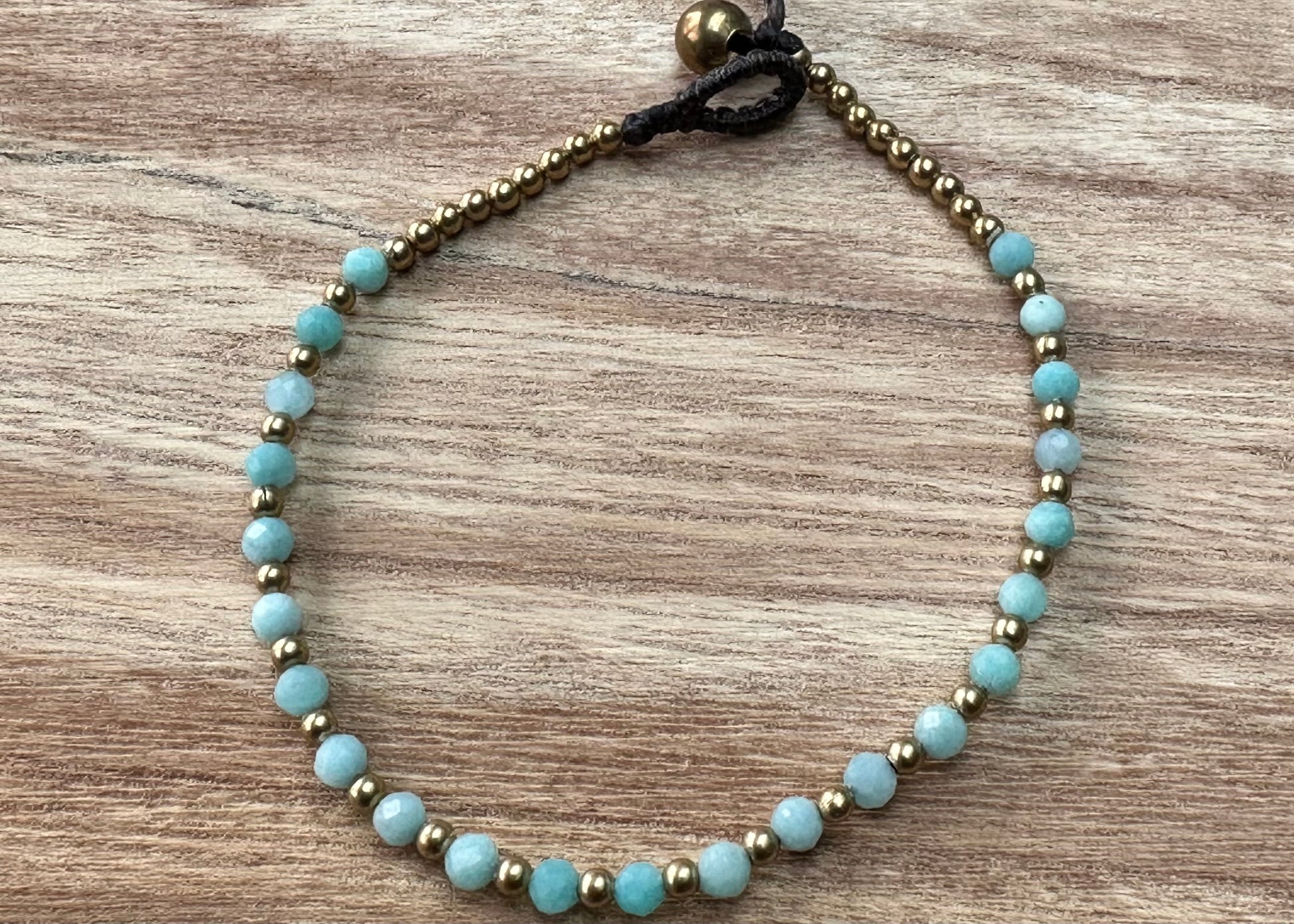 a crystal healing bracelet made of faceted Amazonite crystals on a cotton cord with brass beads