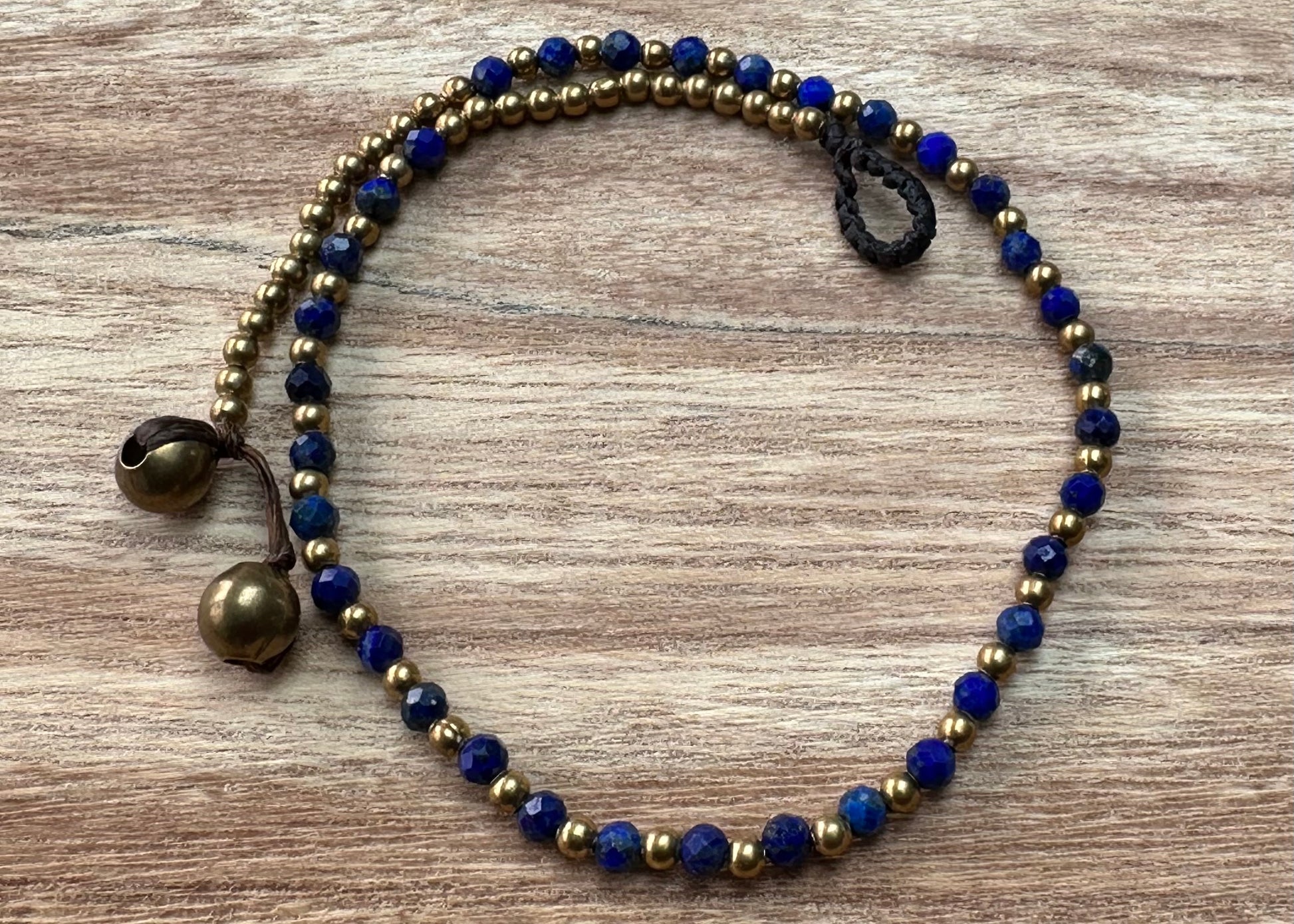 A crystal healing anklet made of faceted Lapis crystals on a cotton cord with brass beads